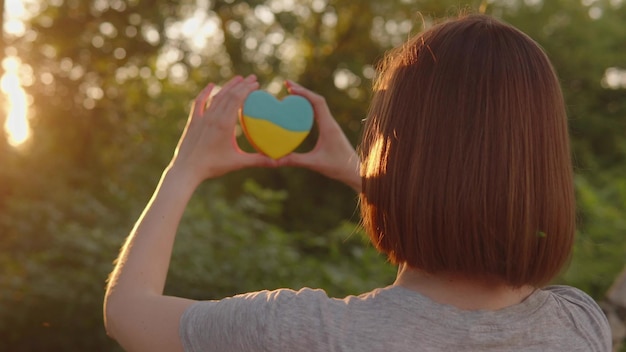 Gingerbread heart in the colors of the Ukrainian flag in the hands of a woman