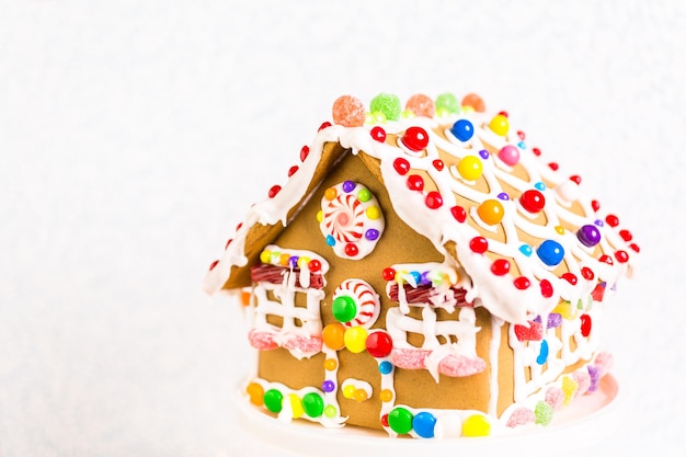 Gingerbread house decorated with white royal icing and bright candies.