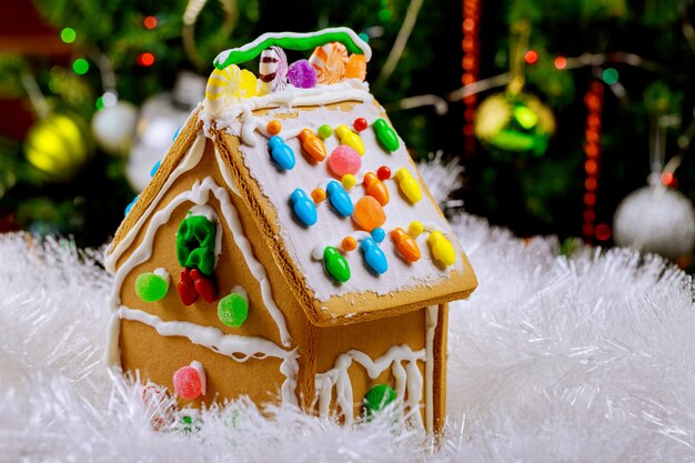 Gingerbread house in snow on decorated christmas tree surface