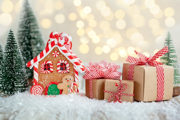 Gingerbread house with many gift boxes on wooden background. Symbol of Christmas and winter holidays.