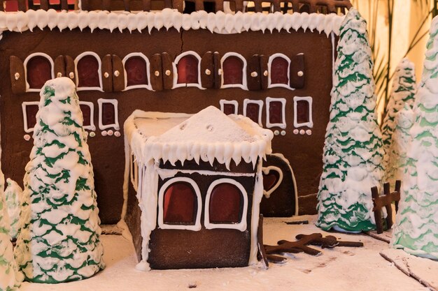 Foto casa di pan di zenzero con ghiaccio bianco e finestre a forma di cuore con alberi di pan dizenzero e gelate bianche