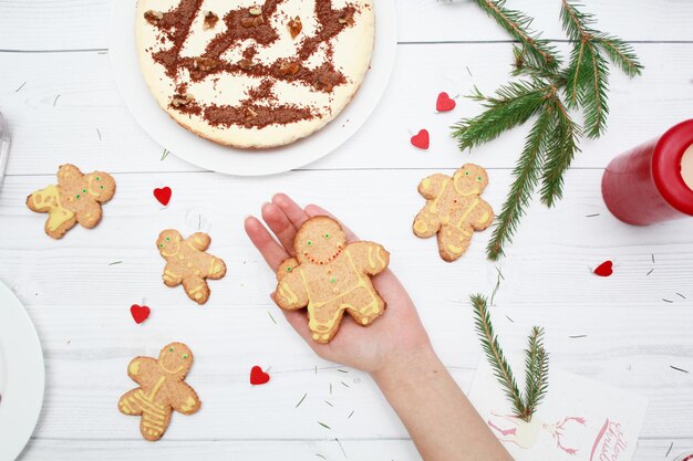 Gingerbread man cookies Cheesecake with chocolate on the wooden background top view Fir branches