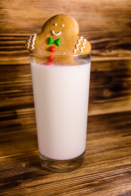 Gingerbread man in a glass of milk on wooden table