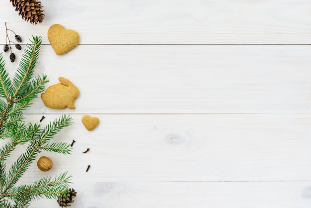 Gingerbread rabbit with a fir branch on a white wooden table.