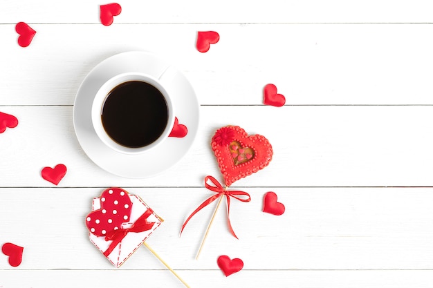 gingerbread in shape of red heart and  envelope for writing, coffee on white wooden background