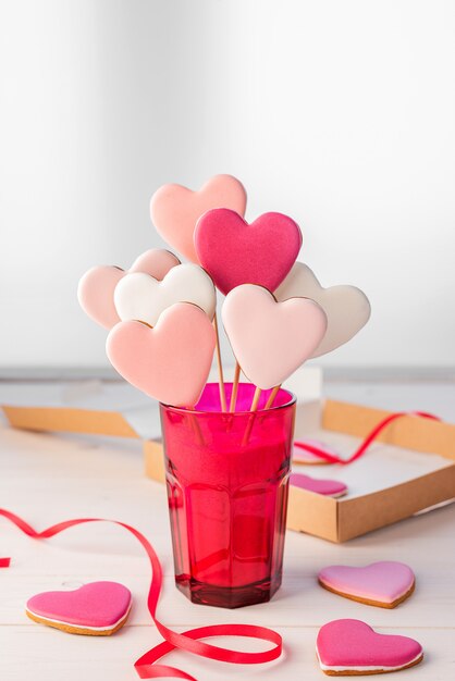 Gingerbread on a stick in the shape of hearts in a bright pink glass on a light table. Valentine's Day.