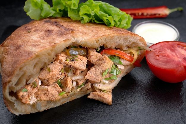 Giras, pita with chicken, sauce and vegetables, on a dark background