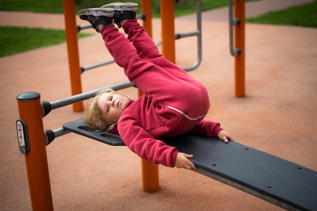 Girl 5 years old blonde in red clothes plays on the playground\
happy childhood