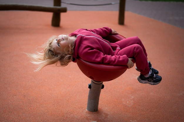 赤い服を着た5歳の女の子が遊び場で遊ぶ幸せな子供時代