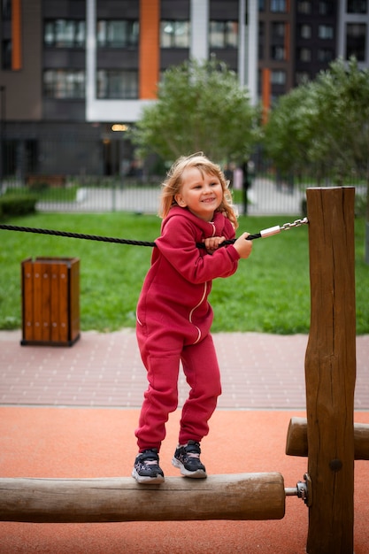 girl 5 years old blonde in red clothes plays on the playground happy childhood