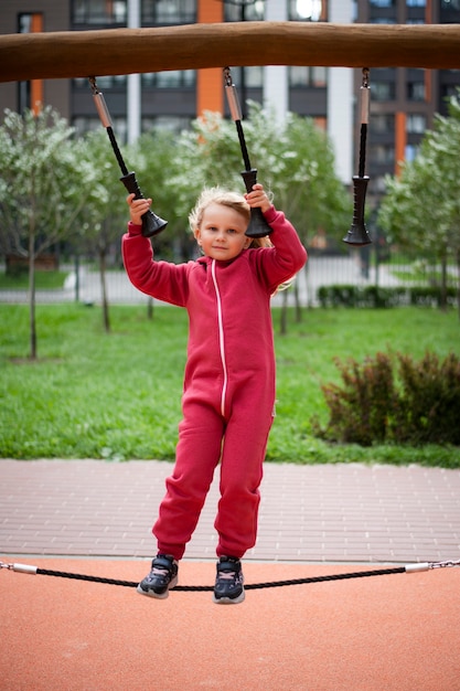 girl 5 years old in a red overalls plays on a sports simulator