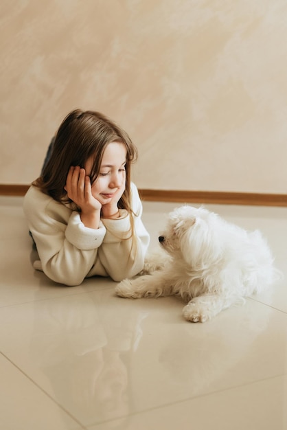 girl 9 years old with long hair model with a pet dog Maltese schoolgirl at home lifestyle