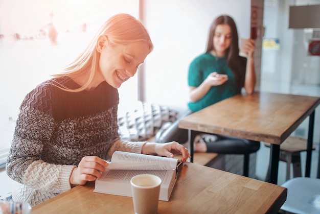 Girl absorbed in reading book during the break in cafe