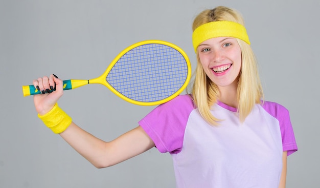 Girl adorable blonde play tennis Sport for maintaining health Active leisure and hobby Athlete hold tennis racket in hand on grey background Tennis sport and entertainment Tennis club concept