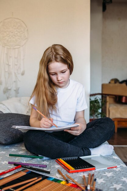 The girl after school plays at home draws with pencils and felttip pens