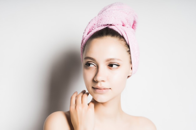 Girl after shower with a towel on her head looking to the side, isolated