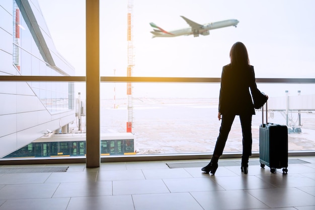 空港の窓の女の子が飛行機を待つ