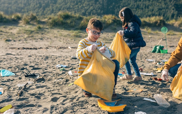 写真 女の子と男の子がビーチからゴミを拾っている