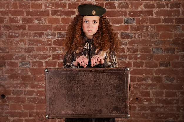 The Girl in army dress in hand with suitcase