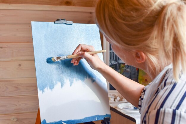 Girl artist paints a picture on canvas at home with oil paints at home