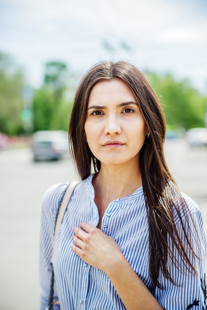 A girl of Asian appearance on a city street. Summer portrait of young Tatar on a blurred background