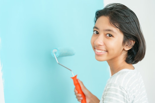 Girl Asian painting wall with the paint roller