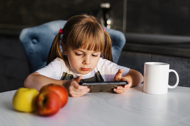 写真 携帯電話で遊んでいるテーブルの女の子