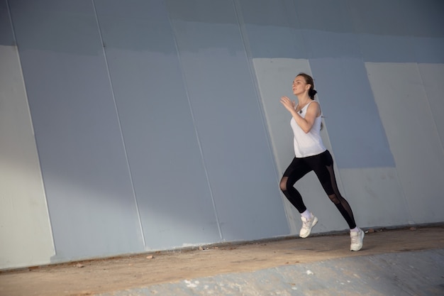 Girl athlete runs under the bridge