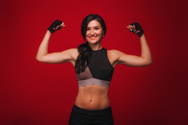 Girl athlete showing biceps on a red background