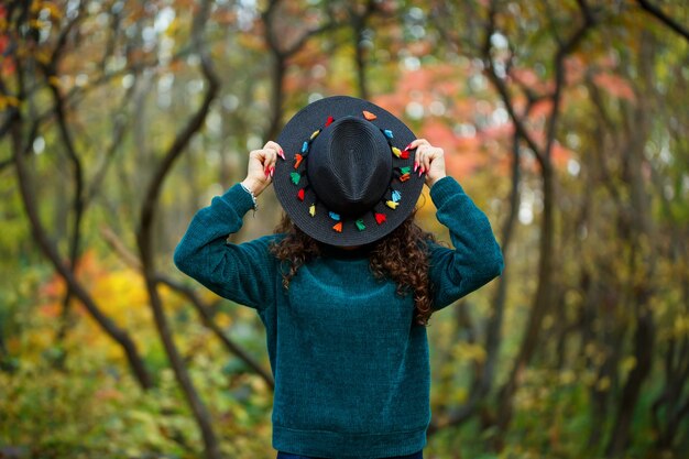 Girl in the autumn forest with a hat in her hands