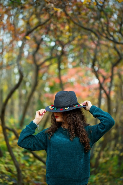 Foto ragazza nella foresta autunnale con un cappello in mano