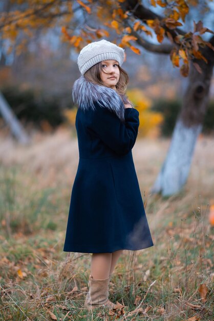 A girl in an autumn garden in a coat and hat