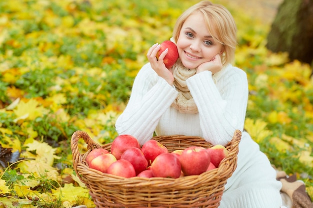 Girl in in autumn park with big basket of apples autumn sale concept