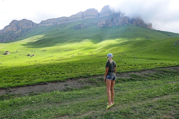 2021년 6월 러시아 코카서스에서 Aktoprak 패스의 녹색 풍경을 배경으로 한 소녀