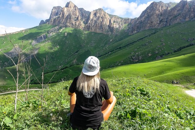 A girl on the background of a green landscape of the Aktoprak pass in the Caucasus Russia June 2021