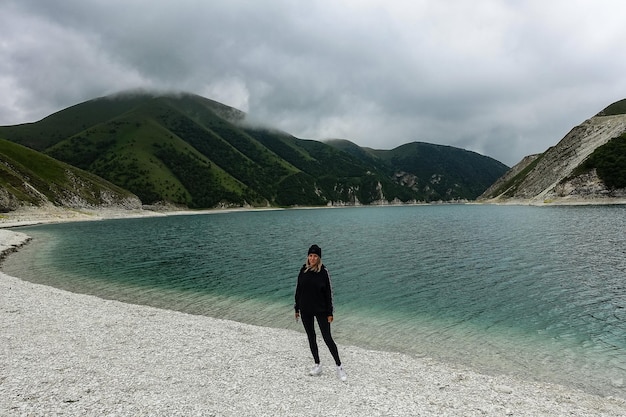 A girl on the background of Lake Kezenoyam in the Caucasus mountains in Chechnya Russia June 2021