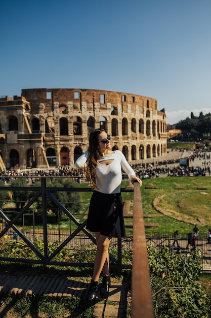 Ragazza sullo sfondo del maestoso antico colosseo a roma.