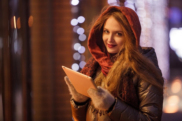 A girl on the background of New Years bokeh with a tablet reads the news