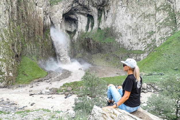 KabardinoBalkaria 코카서스 러시아 영토에 있는 TuzlukShapa 폭포 배경에 있는 소녀