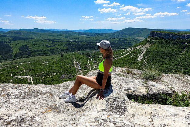 A girl on the background of a view of the Crimean mountains from the cave city of TepeKermen May 2021 Crimea Russia