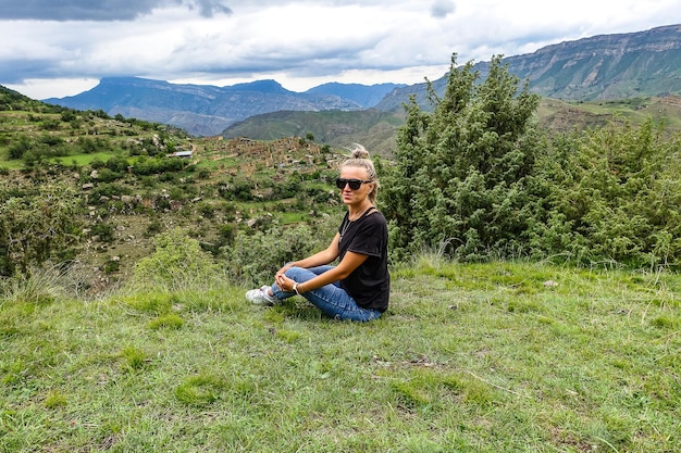 A girl on the background of the village of Kurib in the Caucasus mountains on top of a cliff Dagestan Russia June 2021