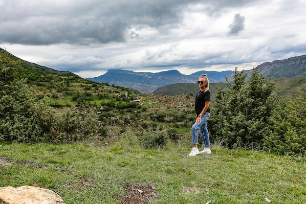 2021년 6월 러시아 다게스탄 절벽 꼭대기에 있는 코카서스 산맥의 쿠리브 마을 배경에 있는 소녀
