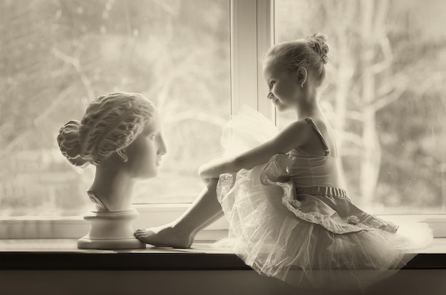 Girl ballerina in a tutu by the window