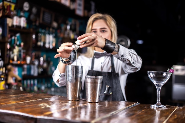 Girl barman mixes a cocktail behind the bar