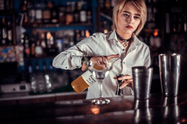 Girl barman mixes a cocktail in the taproom