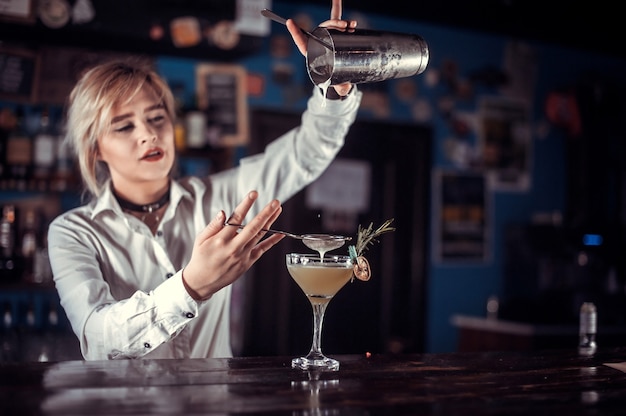 Девушка-бармен делает коктейль в баре