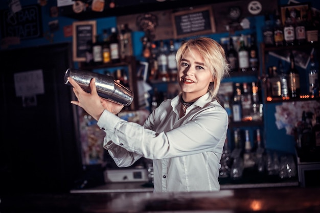 Девушка-бармен смешивает коктейль в пивной