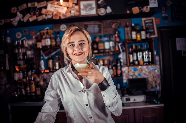 Девушка-бармен смешивает коктейль в пивном ресторане