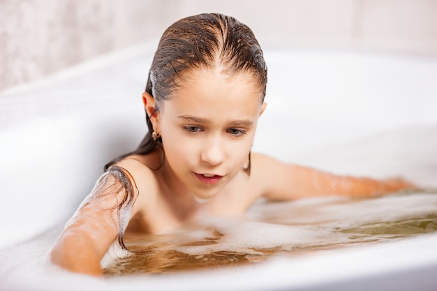 Girl bathes in a bathtub with foam and has fun during quarantine at home