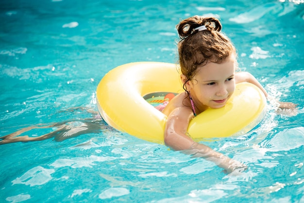 The girl bathes in the pool in blue goggles for swimming